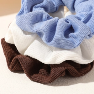 Detail of ribbed texture and soft folds on blue, white, and brown scrunchies