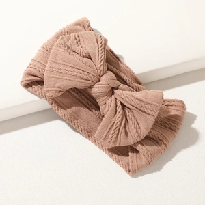 Dettaglio fascia per neonati in maglia rosa con trama jacquard e grande fiocco morbido
