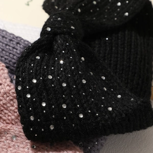 Detail of hand-knitted black headband with sparkling rhinestones and twisted knot design