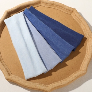 Detail of four gradient blue knitted elastic headbands with fine ribbed texture on a stone tray