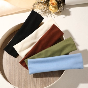 Five elastic yoga headbands in various colors arranged on a rustic wooden tray