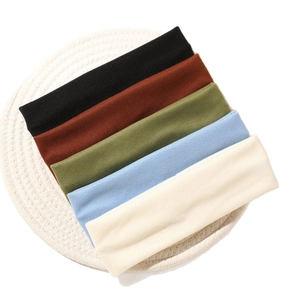 Set of five elastic non-slip yoga headbands in various colors on a white woven coaster