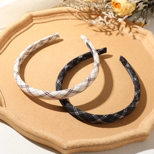 Close-up of handmade plaid headband set in beige and black on a rustic tray