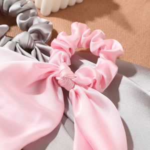 Detail of satin bow scrunchies with long ribbons in pink and silver grey silky fabric