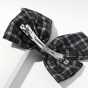 Detail of the silver metal spring clip on a vintage black and white plaid bow hair claw