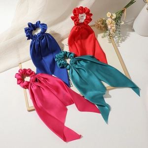 Flat lay of colorful satin bow scrunchies with long streamers in four vibrant shades