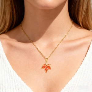 Detailed close-up of golden maple leaf necklace with orange rhinestones on model