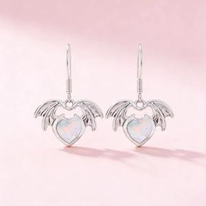 Boucles d'oreilles ailes de chauve-souris gothiques avec opale coeur sur fond rose