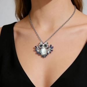 Fashionable owl pendant necklace with moonstone and colored crystals on a black V-neck top