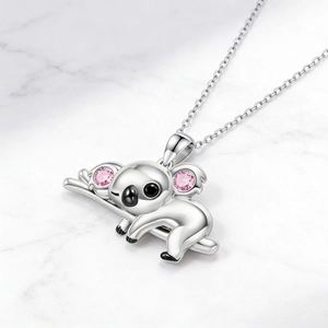 Collar con colgante de koala rosa y cadena de metal plateado sobre fondo de mármol