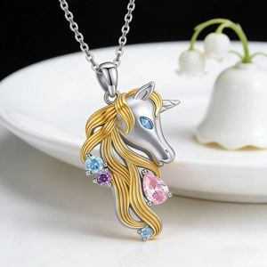 Macro shot of silver and gold unicorn pendant with colorful crystals on ceramic plate