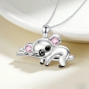 Primer plano de un colgante de koala plateado con piedras rosas en collar fino