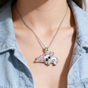Primer plano del collar con colgante de koala y piedras rosas sobre modelo con denim