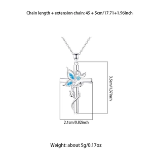 Détail du collier croix argenté avec motifs papillon et pierres bleues serties