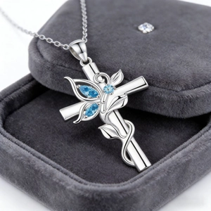 Vue macro du collier croix en argent avec pierres bleues sur boîte à bijoux en velours