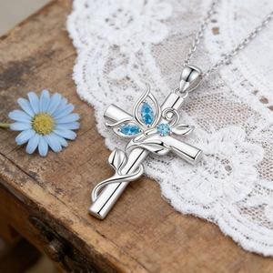 Collier croix argentée avec motif de feuilles et pierres bleues sur bois vintage