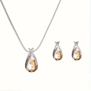 Detail view of silver drop necklace and earrings set with champagne crystals on white base