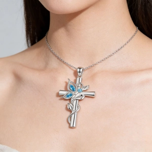Détail du collier croix en argent avec papillon bleu porté sur le cou du modèle
