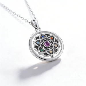 Macro shot of silver chakra necklace featuring colorful stones and lotus mandala pendant