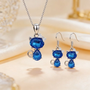 Detail view of blue cat-shaped crystal necklace and earrings set on beige silk fabric