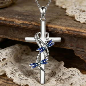 Elegante collar de cruz con libélula plateada y alas de esmalte azul en fondo de madera