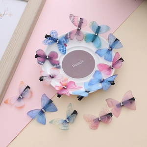 Detail of colorful embroidered tulle butterfly hair clips with sparkling rhinestone center