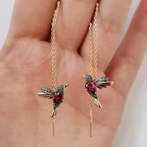 Dettaglio degli orecchini a forma di colibrì dorato con cristalli rossi e verdi lucidi