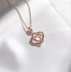 Macro detail of rose gold interlocking double heart pendant necklace with rhinestones