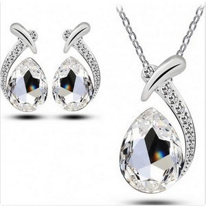 Elegant silver jewelry set with teardrop crystals and small diamonds on white background