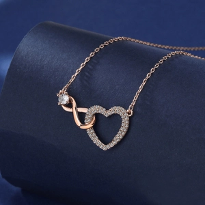 Dettaglio macro della collana cuore infinito in oro rosa con cristallo su seta blu
