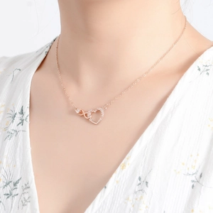 Dettaglio della collana cuore infinito in oro rosa con zirconi indossata da una modella