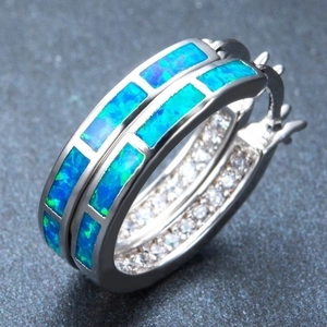Macro shot of silver hoop earrings with blue opal inlay and white zircon details