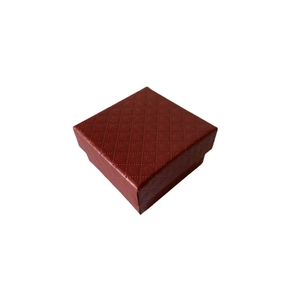 Détail d'un écrin à bijoux carré rouge avec texture gaufrée en diamant pour bagues