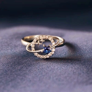 Saturn planet ring with blue star stone and sparkling crystals on purple silk background