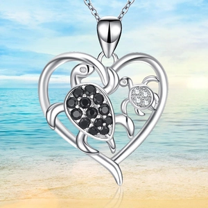Silver turtle heart necklace with black crystals on a tropical beach background