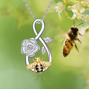 Infinity pendant necklace featuring a silver rose and gold bee with a nature background
