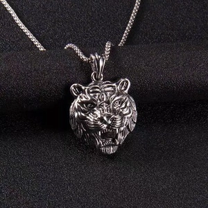 Macro close-up of a vintage silver tiger head pendant with detailed textured chain
