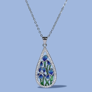 Detail of teardrop pendant with blue enamel flowers and pavé crystals on the silver edge