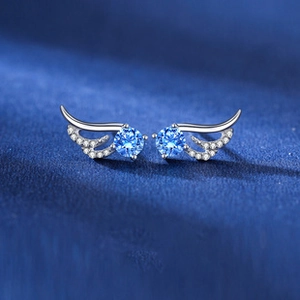 Detail of angel wing stud earrings with blue round stones and micro-pave crystals