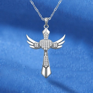 Close-up of silver-tone cross necklace with angel wings and sparkling cubic zirconia stones