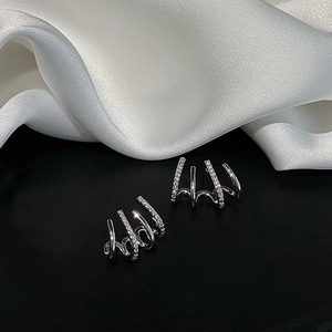 Minimalist S925 silver needle four-claw diamond curved stud earrings on silk background
