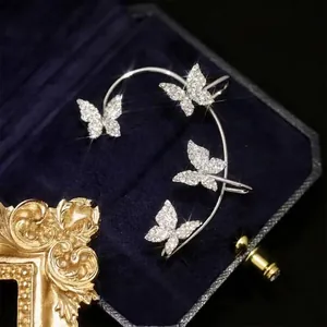 Detailed view of silver butterfly ear cuffs with sparkling crystals on a velvet box