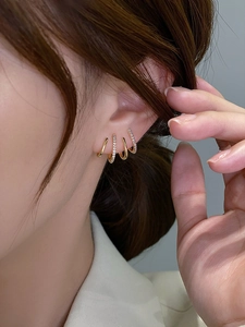 Detail of four-claw curved stud earrings with inlaid zircon on a gold-plated needle
