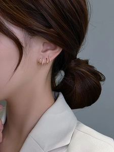 Detail of model wearing a set of gold s925 silver hoop earrings with zircon accents