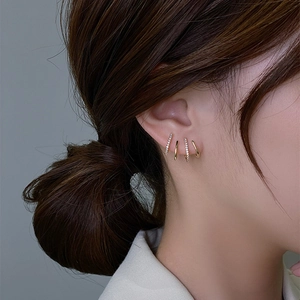 Close-up of golden multi-layered hoop earrings featuring sparkling zircon stone settings