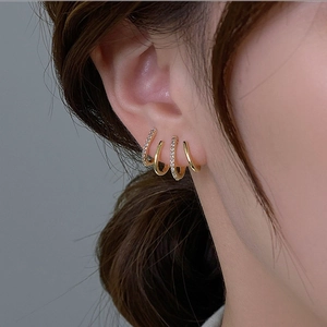 Detailed view of gold multi-layer curved earring with sparkling zircon stone inlay