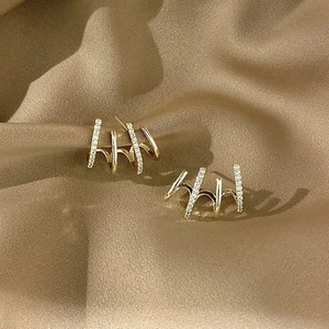 Macro shot of gold four-claw curved earrings with shimmering white cubic zirconia accents