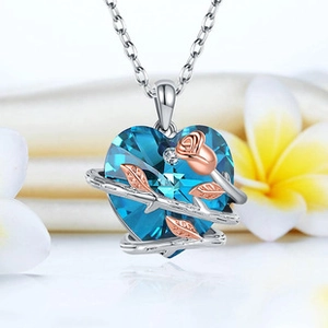 Close-up of blue heart crystal necklace with rose gold flower and silver chain