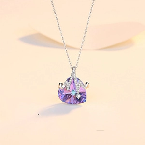 Macro shot of heart-shaped purple crystal pendant with diamond-encrusted silver design