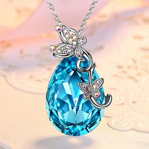Detailed close-up of infinity heart necklace featuring a blue crystal and butterfly design
